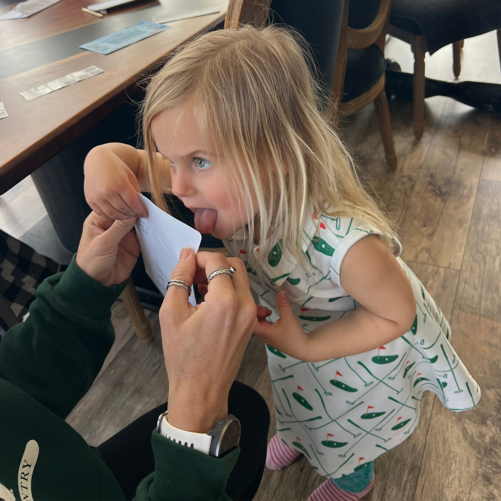 Child interacting with an adult at a dining table sealing an envelope to send out